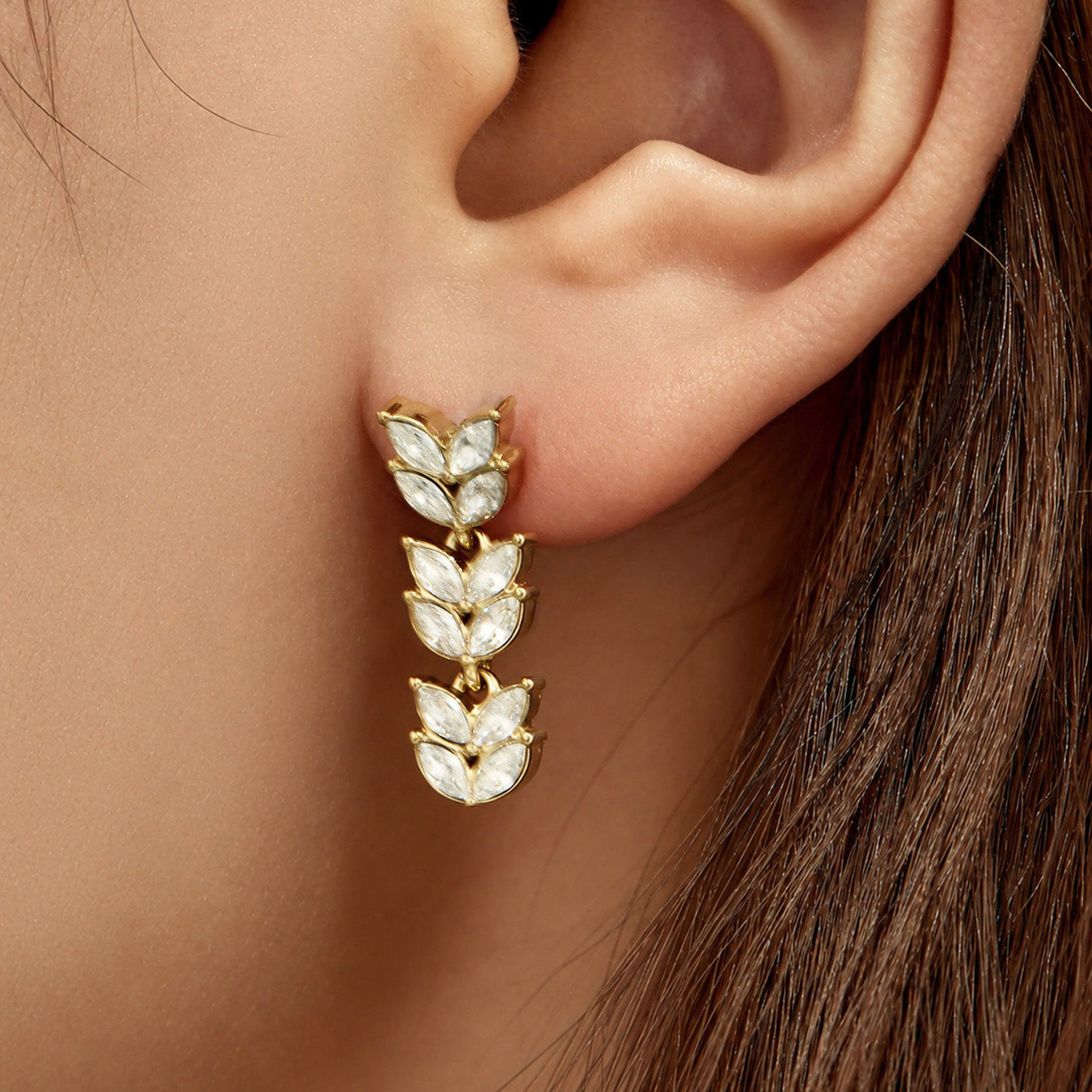 Model wearing botanical cubic zirconia drop earrings in gold