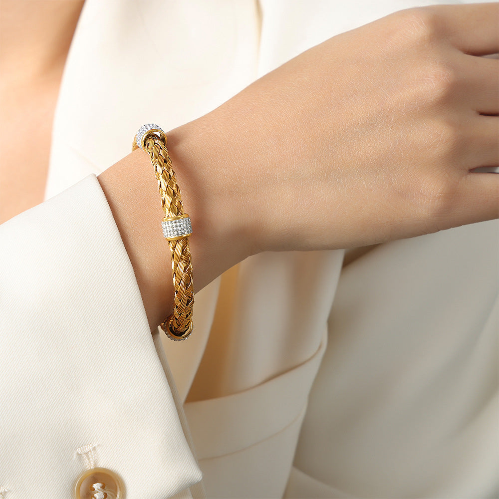 Close-up of a gold braided stainless steel cuff bangle worn on a model wrist