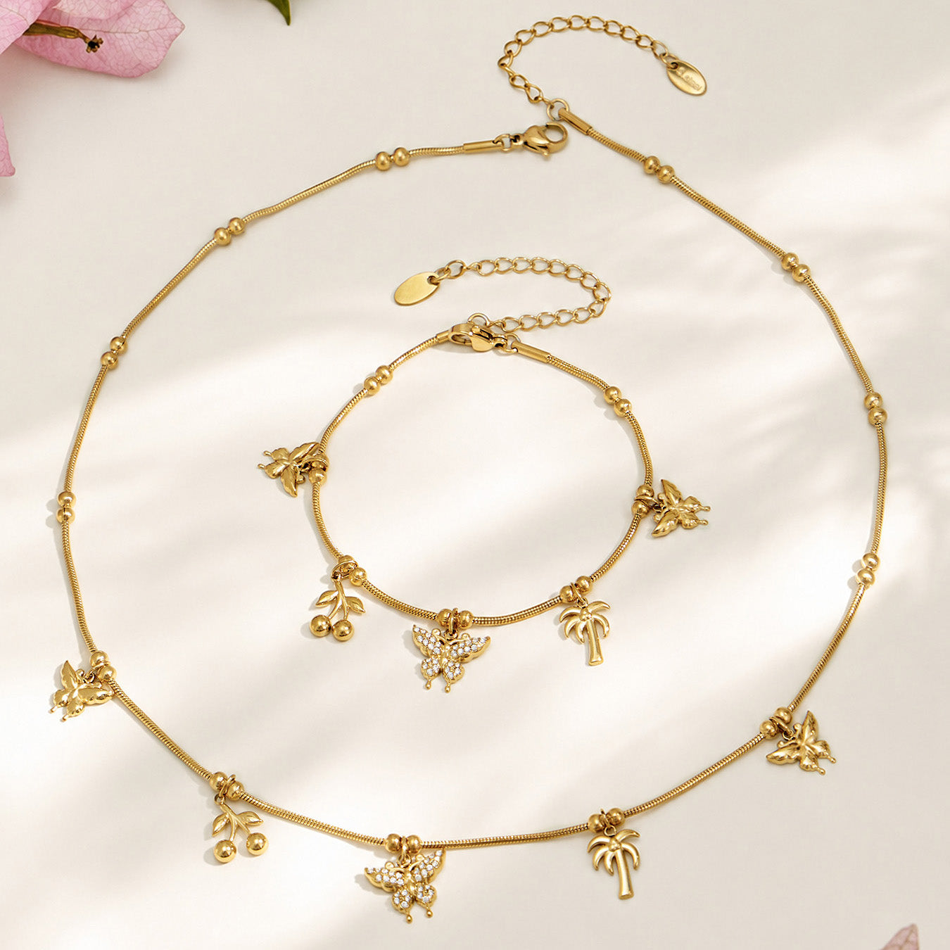 Gold butterfly charm necklace and bracelet assortment displayed on a neutral background