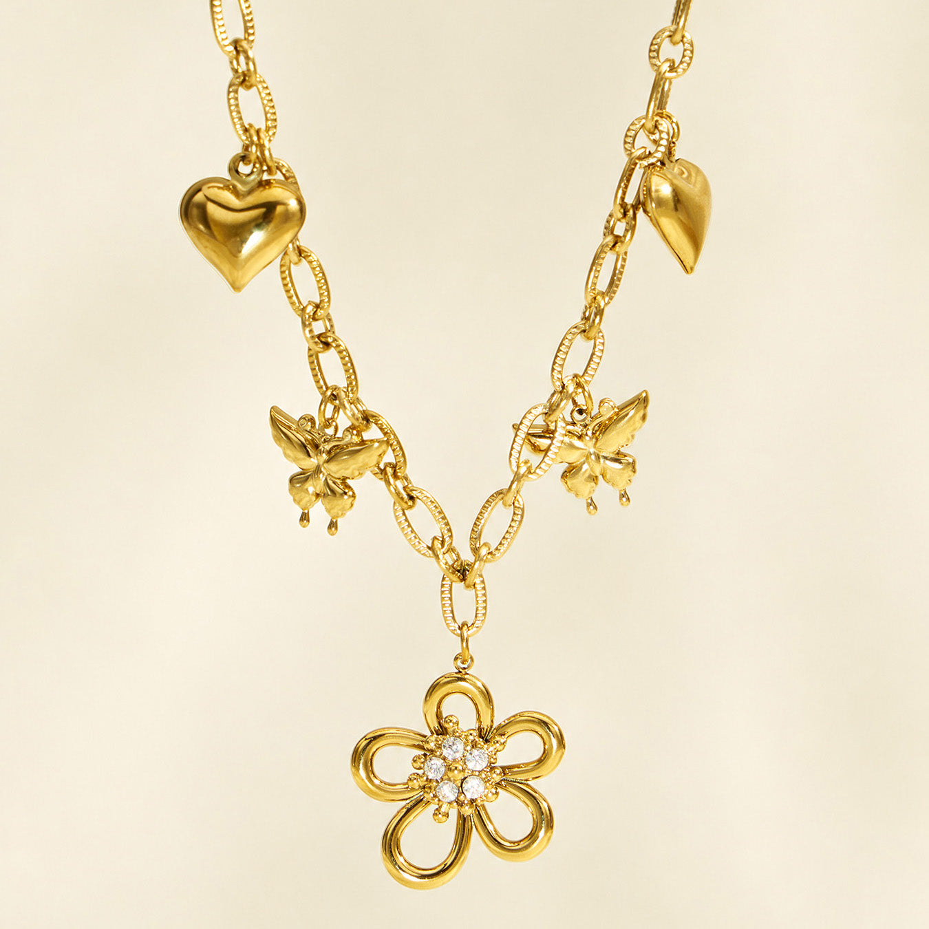 Gold charm necklace with butterfly flower and heart pendants in detailed view