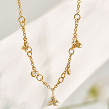 Gold butterfly zircon necklace with delicate dangling charms displayed on white
