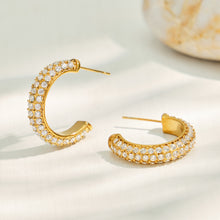 Gold C-shaped pavé cubic zirconia hoop earrings displayed on a neutral background