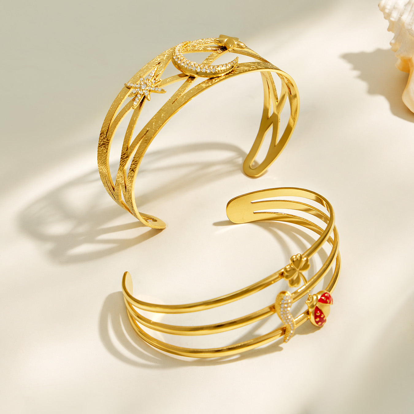 Gold celestial and chili pepper open cuff bracelets arranged together in a flat lay