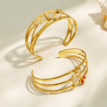 Gold celestial and chili pepper open cuff bracelets arranged together in a flat lay