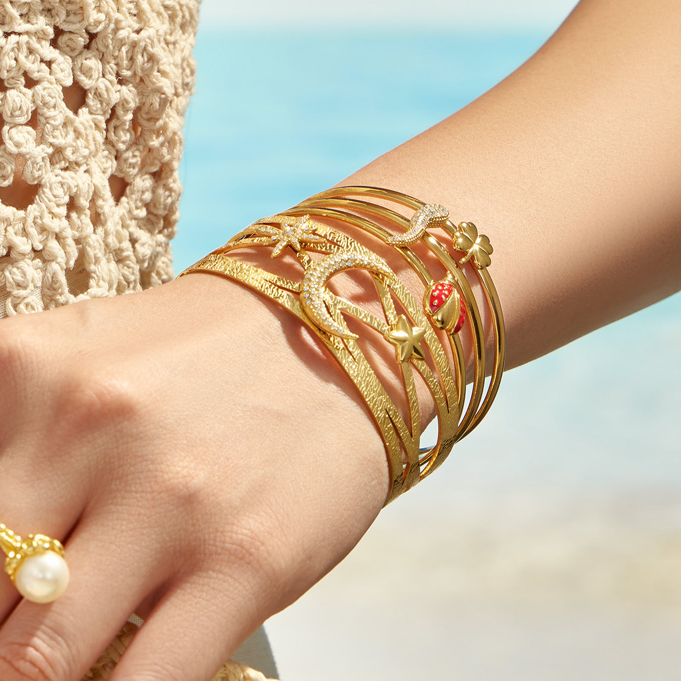 Gold celestial and chili pepper statement cuff bracelets styled together on the wrist