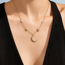 Front view of a model wearing a gold celestial necklace with star and moon charms
