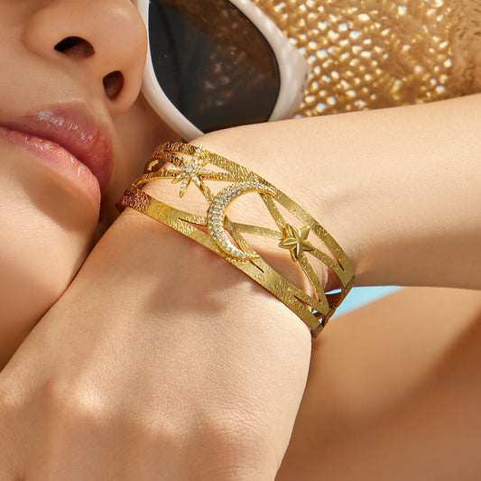 Model wearing a gold celestial cuff bracelet with star, moon and zircon details