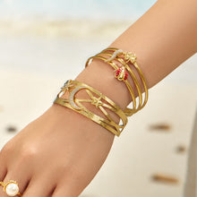 Gold chili pepper open cuff bracelet worn on a model wrist at the beach