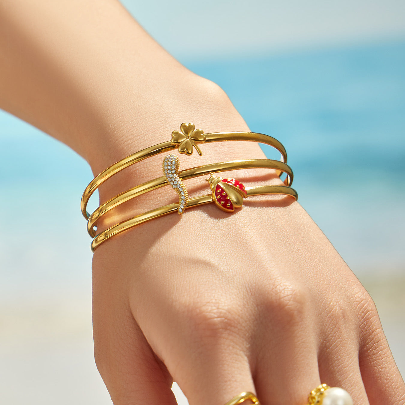 Model wearing a gold chili pepper cuff bracelet with layered open bands