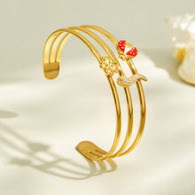 Gold open cuff bracelet with a red chili pepper charm displayed on a neutral background