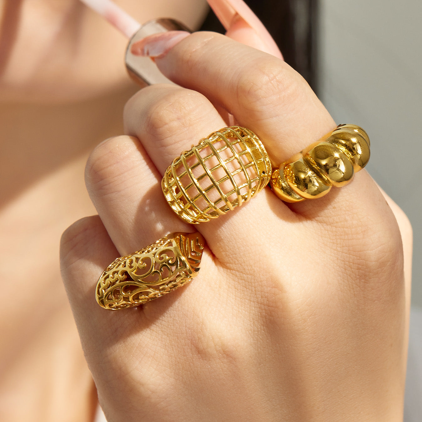 Close-up of chunky gold tone 316L stainless steel rings styled on a model hand