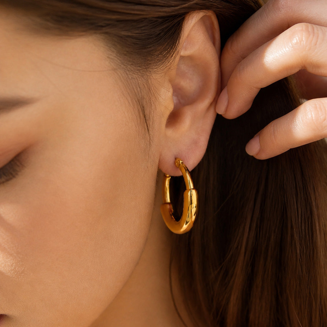 Close-up of chunky gold hoop earrings styled on the ear