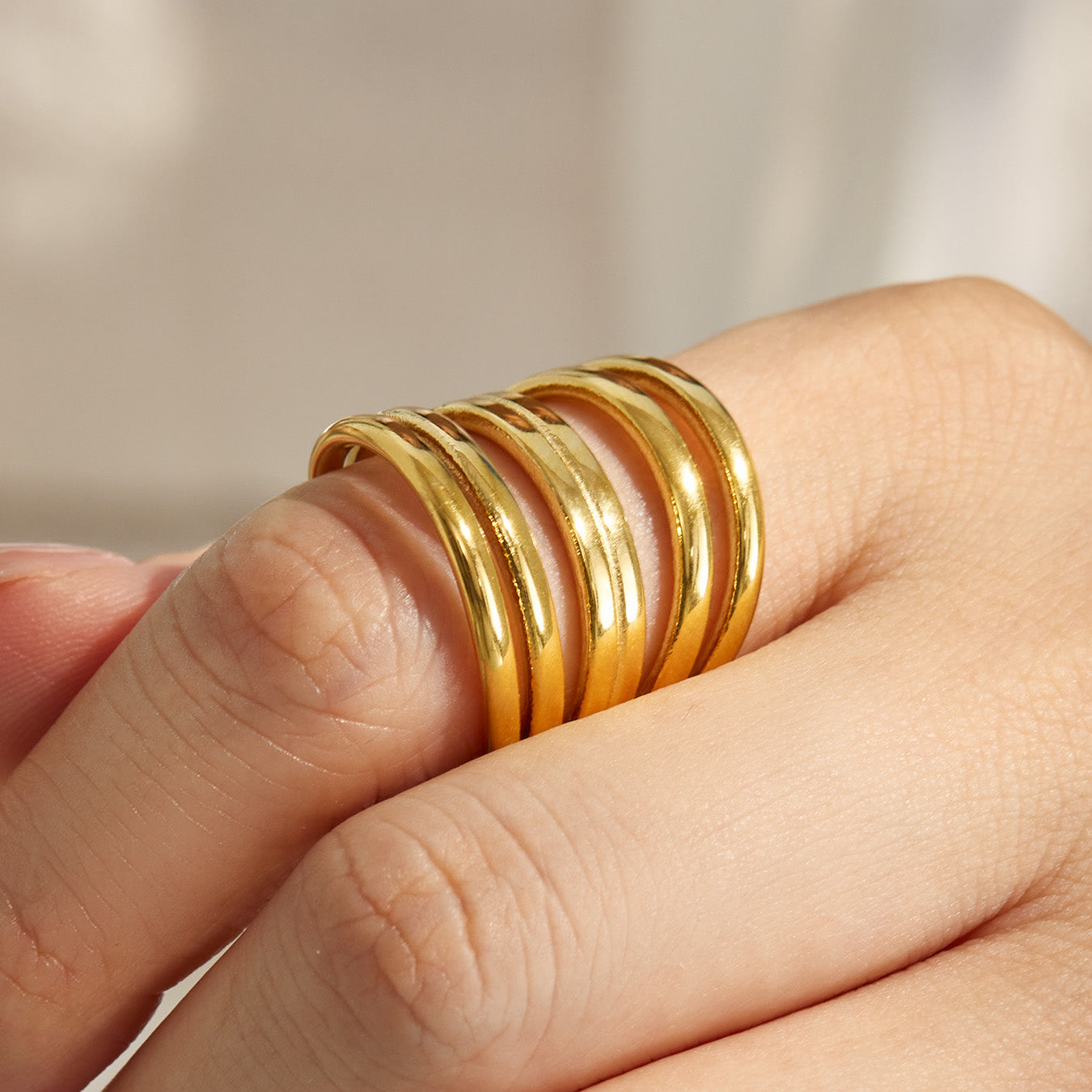 Gold tone chunky 316L stainless steel multi-band open ring worn on a model hand
