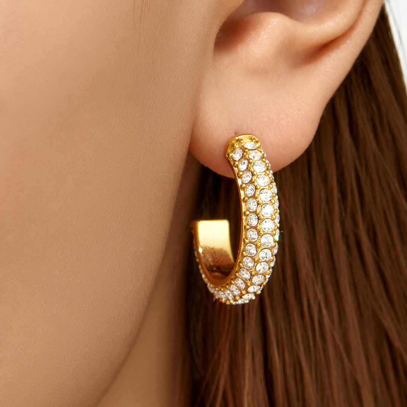 Model wearing chunky gold pavé CZ hoop earrings on the earlobe