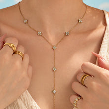 Gold-tone clear stone Y necklace with small floral motifs shown in a close-up neckline view