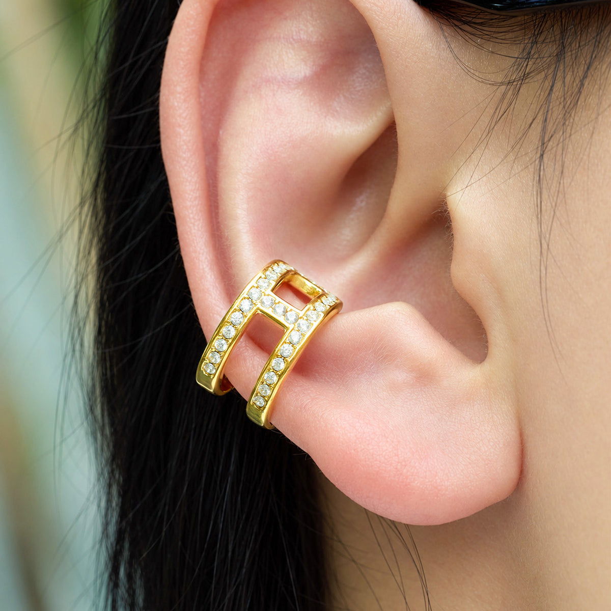 Gold-tone stainless steel clip-on ear cuff with rhinestone details worn on ear