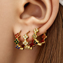 Close-up of gold four-leaf clover CZ huggie earrings styled on the earlobe