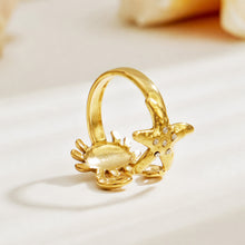 Side view of a gold crab and starfish open ring in 316L stainless steel with sculptural marine details