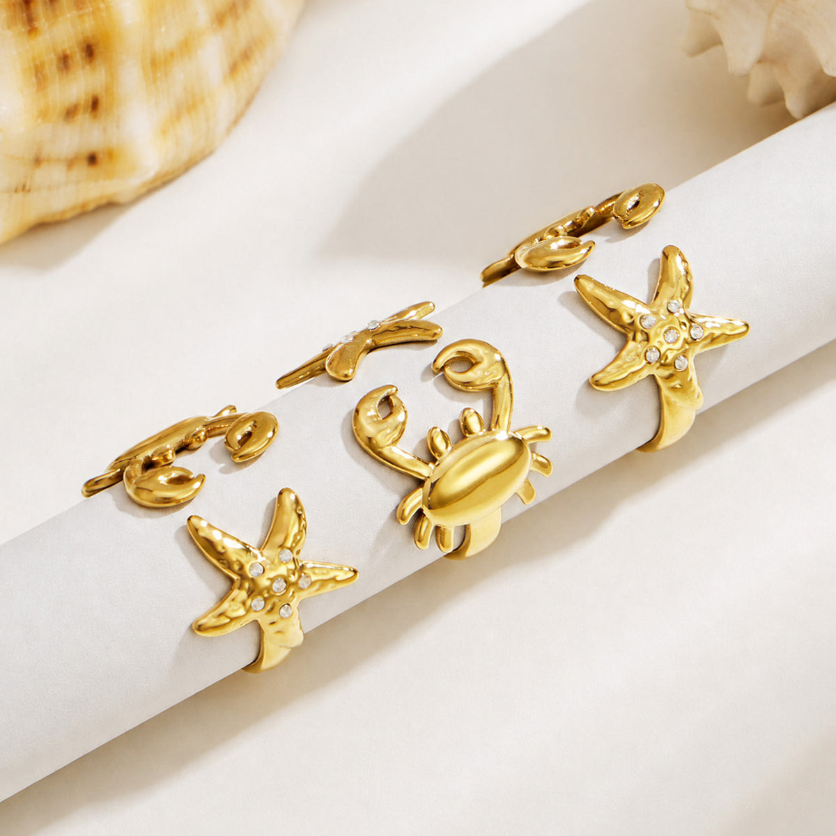 Gold crab and starfish open rings displayed together on a light background for coastal jewelry styling