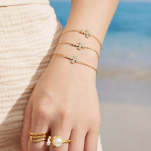 Model wearing a delicate gold cross chain bracelet with an extender