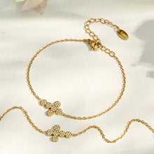 Gold cross zircon necklace and bracelet options arranged on a soft ivory surface