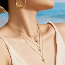 Side-profile model wearing a minimalist gold cross pendant necklace