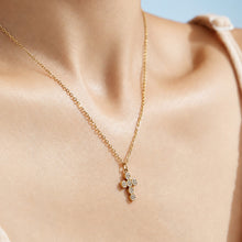 Model neckline showing a small gold cross zircon pendant necklace