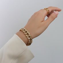 Model wearing a chunky gold Cuban link bracelet with clear cubic zirconia on the wrist