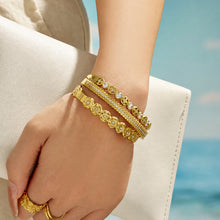 Outdoor view of a model wearing layered gold cubic zirconia bangles