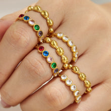 Gold beaded rings with white and colorful CZ details stacked on a model hand