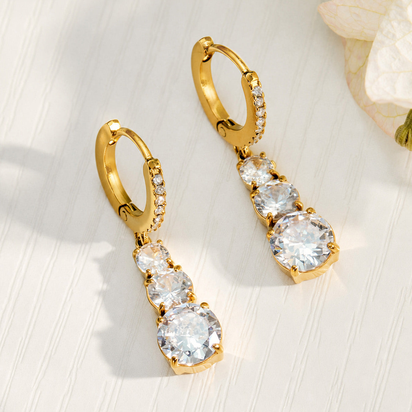 Gold cubic zirconia drop earrings displayed on a light background