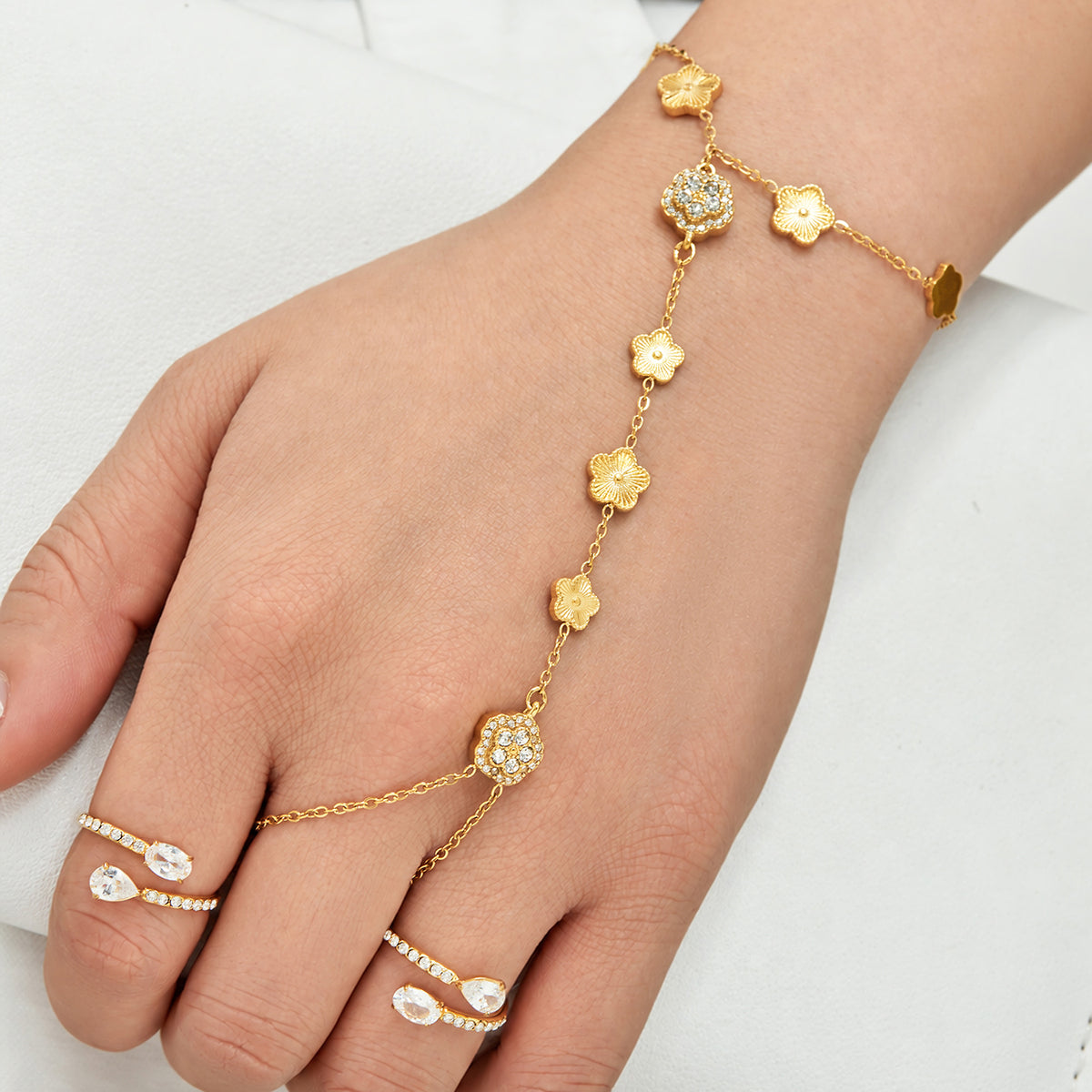 Gold-tone CZ floral hand chain bracelet worn with connected finger ring