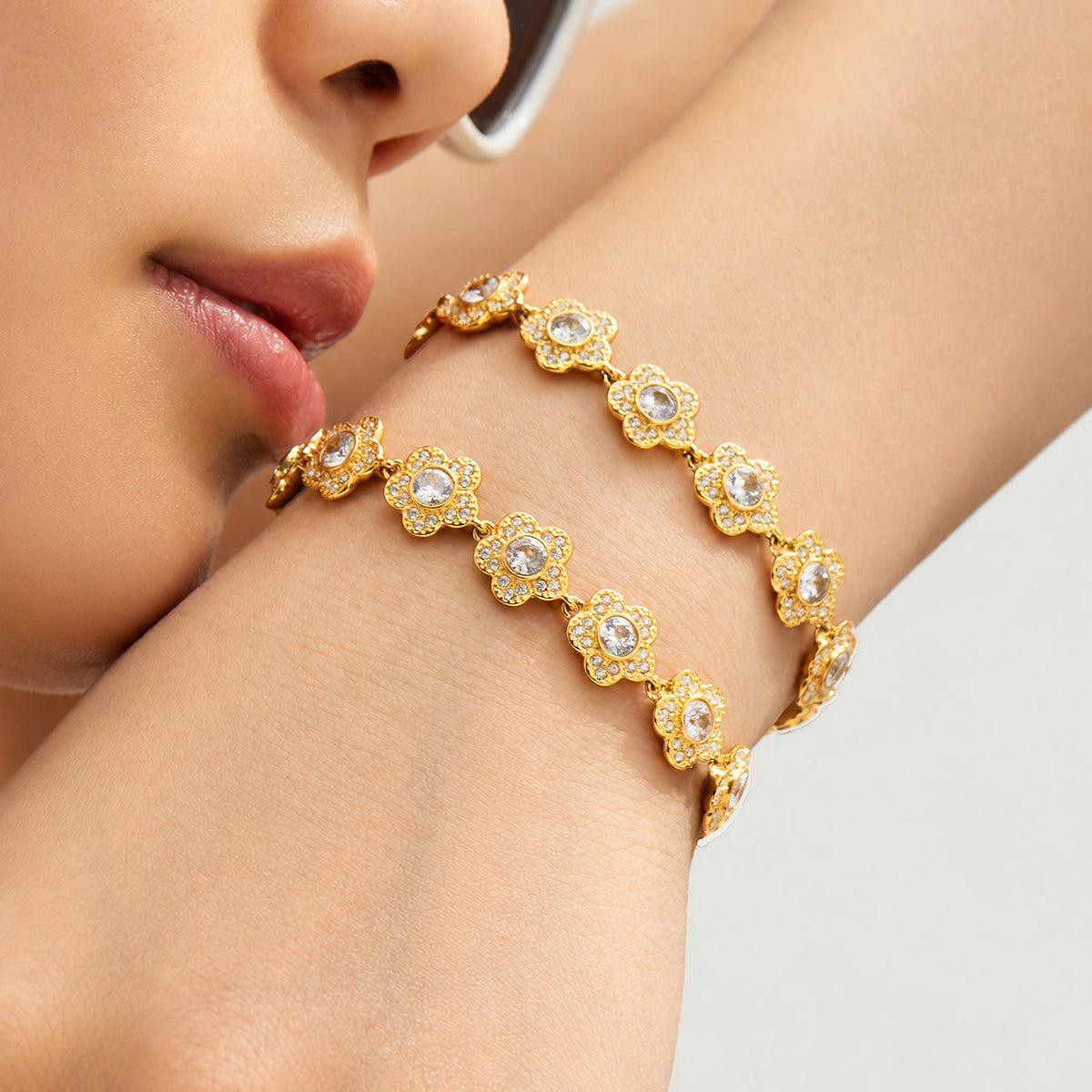Gold-tone cubic zirconia flower bracelets worn together on the wrist in close-up view