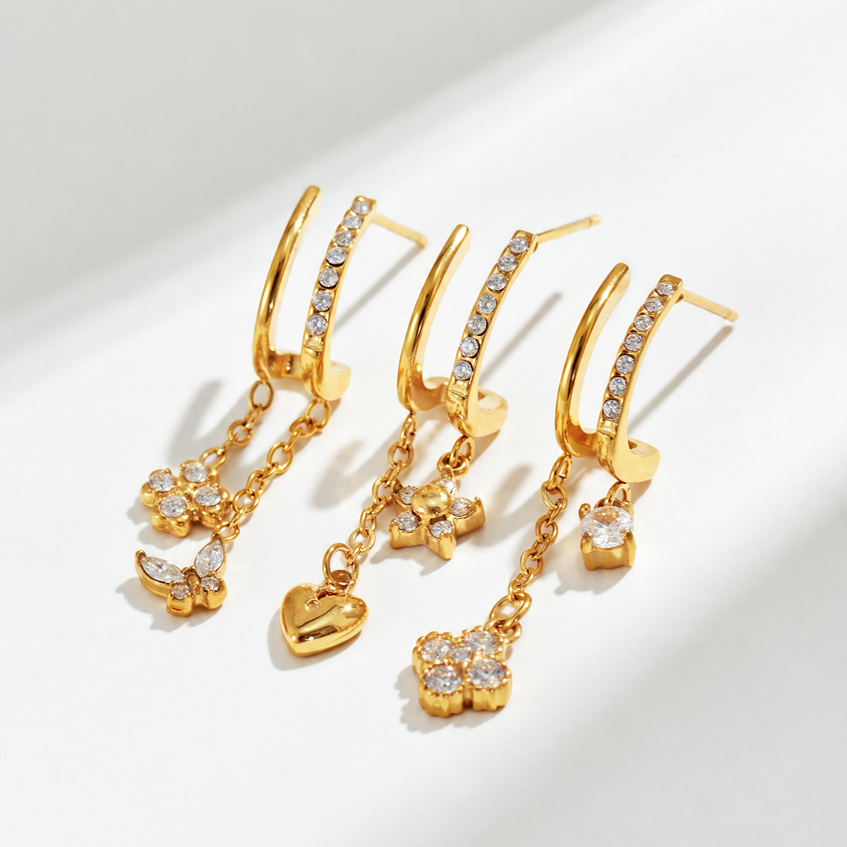 Gold-tone stainless steel CZ flower and butterfly drop earrings displayed together