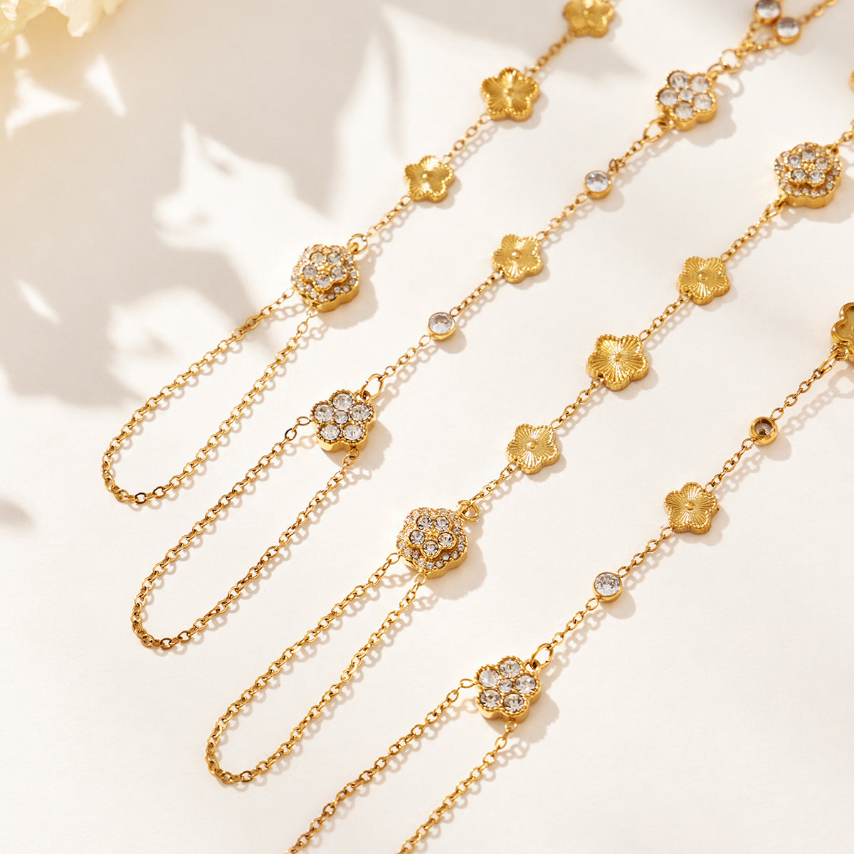 Gold-tone stainless steel hand chain bracelet with cubic zirconia flower details shown close up