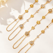 Gold-tone stainless steel hand chain bracelet with cubic zirconia flower details shown close up