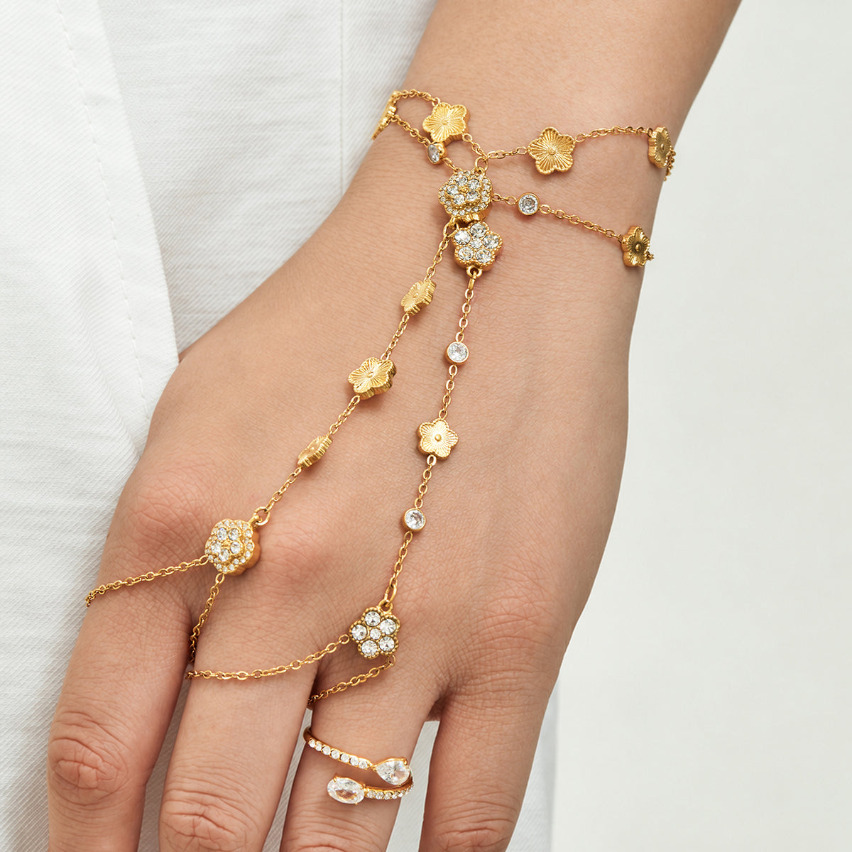 Gold-tone stainless steel CZ hand chain bracelet extending from wrist to finger