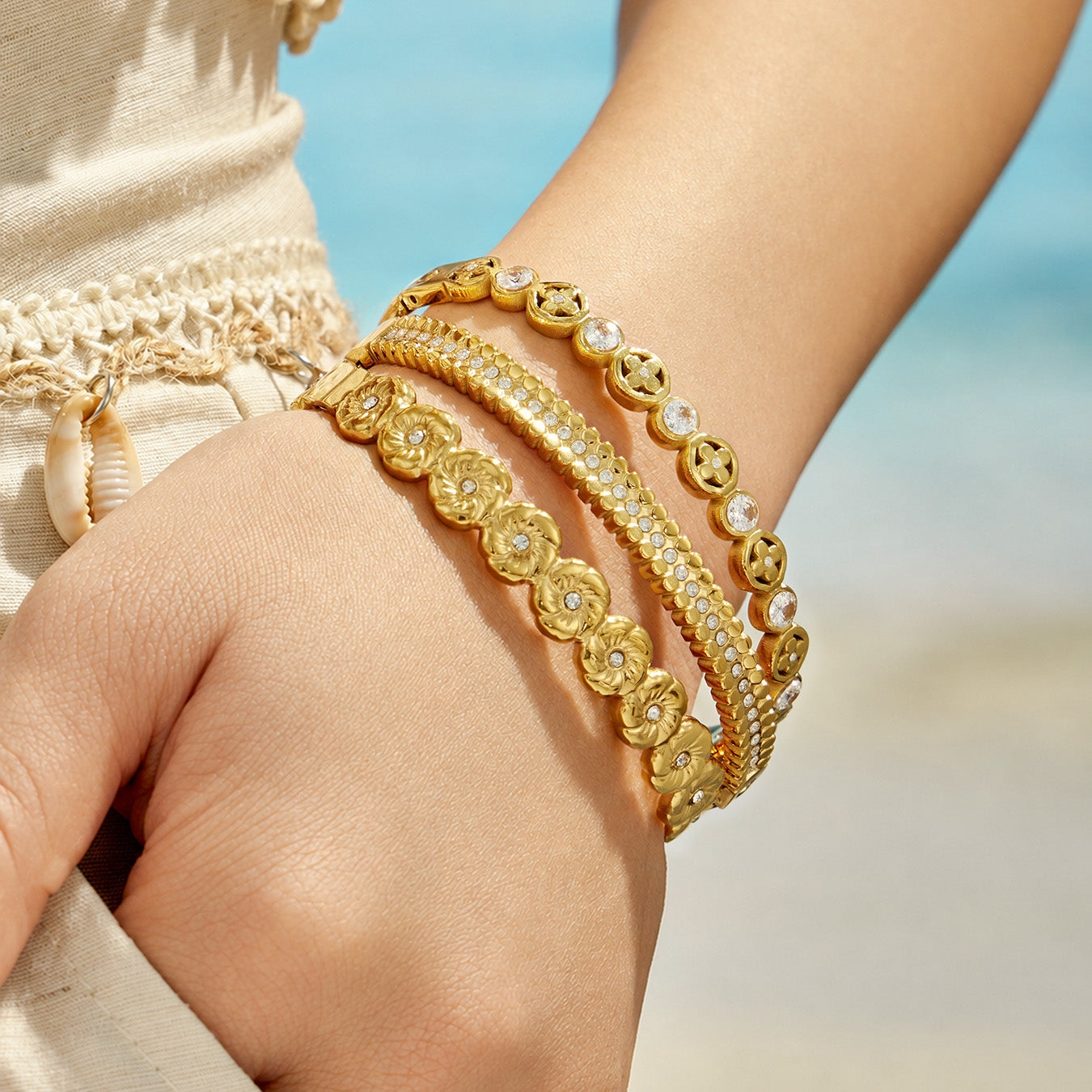 Hand close-up of layered gold cubic zirconia hinged bangle bracelets