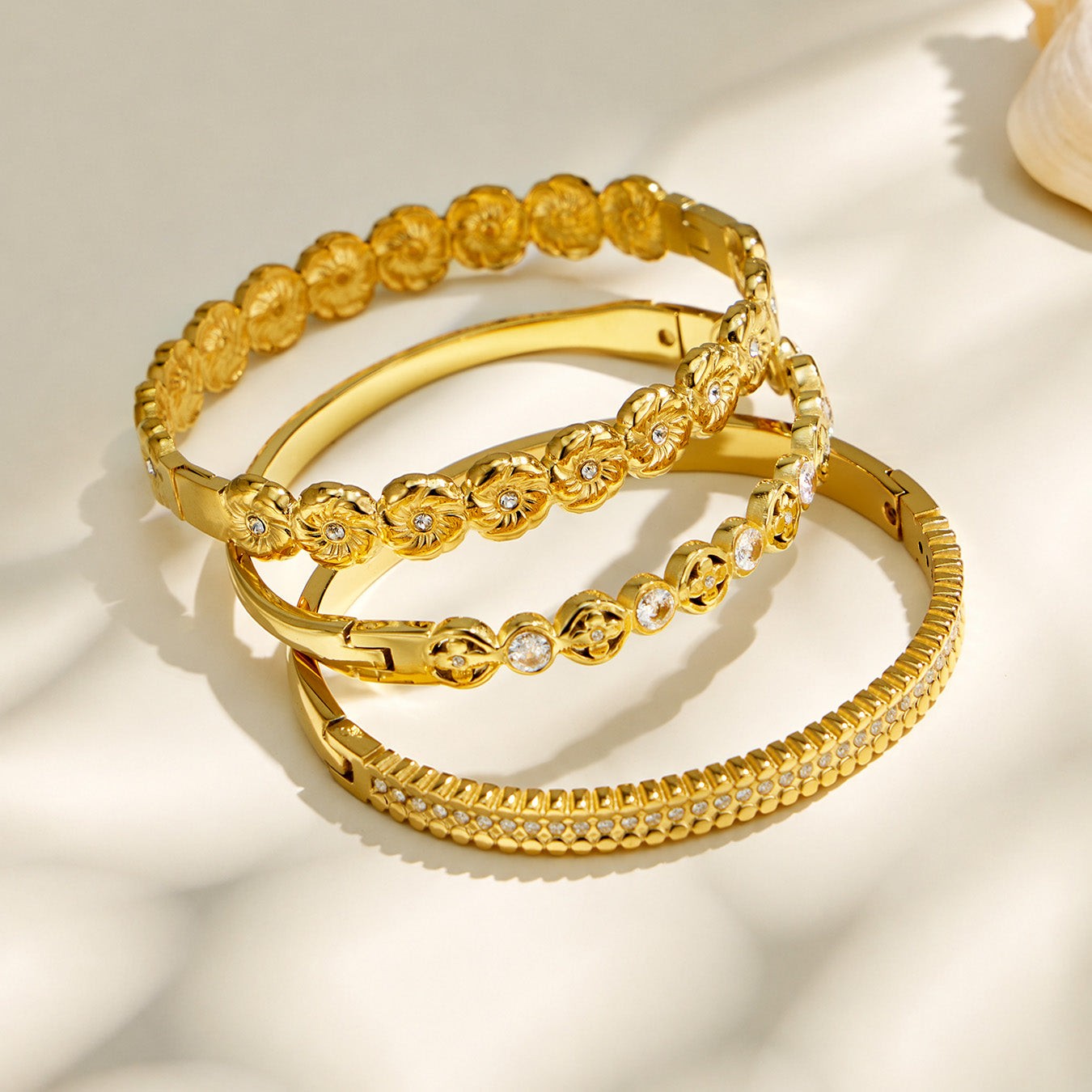 Gold cubic zirconia hinged bangles arranged in a stacked product display