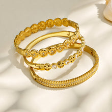 Gold cubic zirconia hinged bangles arranged in a stacked product display
