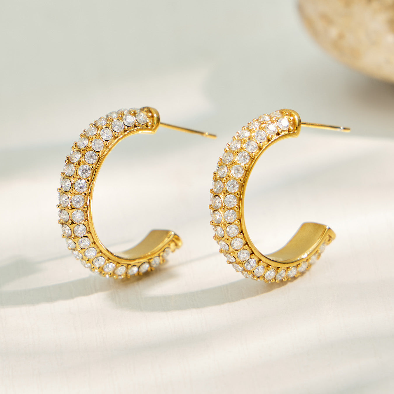 Pair of gold C-shaped hoop earrings with clear pavé cubic zirconia