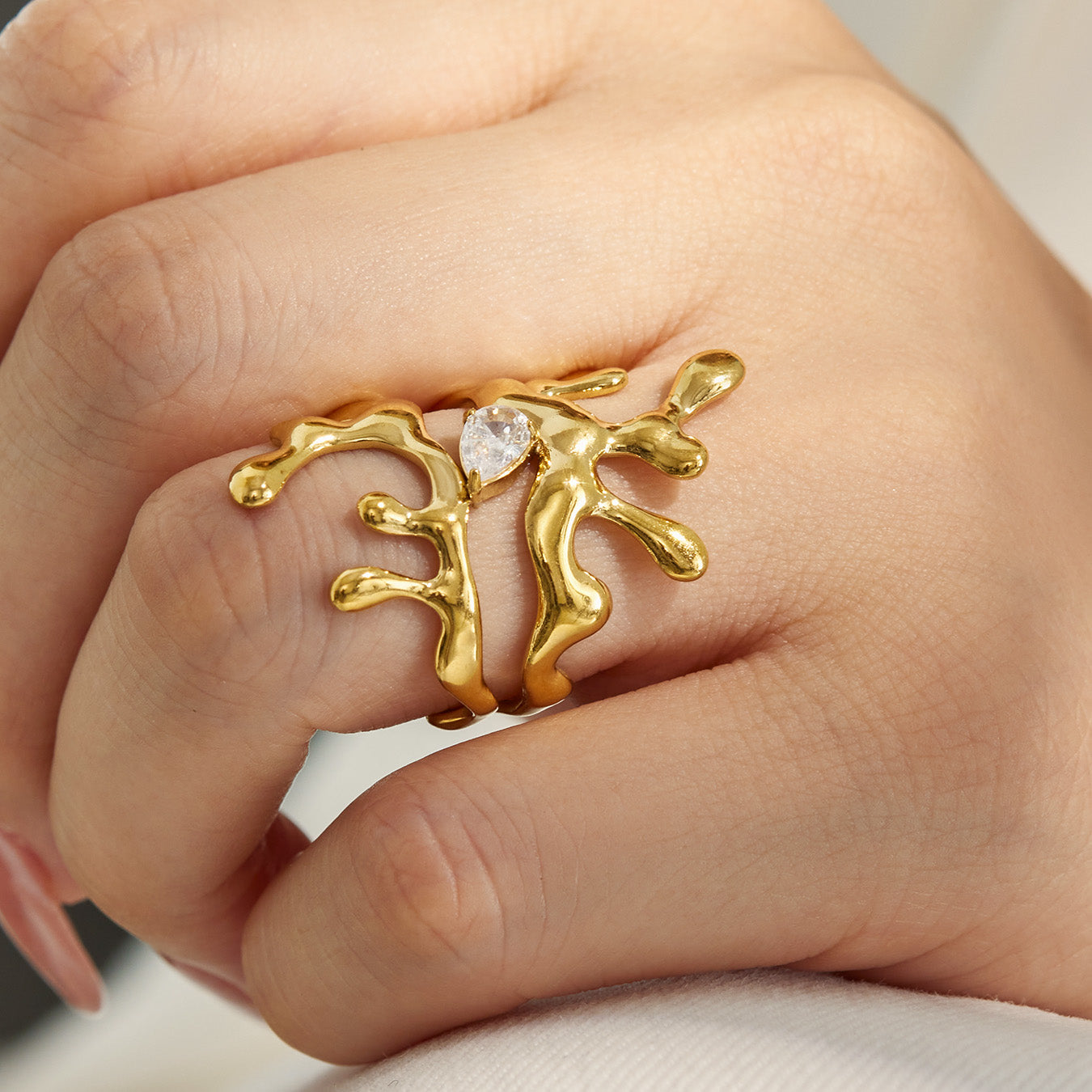 Model wearing a gold 316L stainless steel irregular CZ statement ring with sculptural design