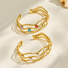 Gold cubic zirconia open bangles arranged in a stacked product display