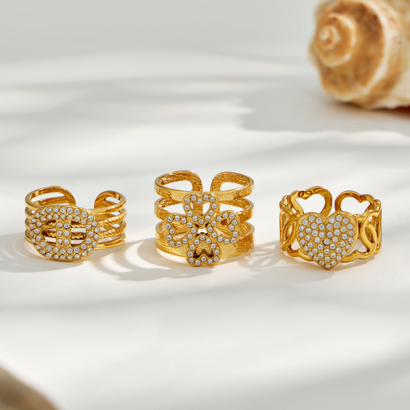 Four gold 316L stainless steel CZ open ring designs displayed together on a light background