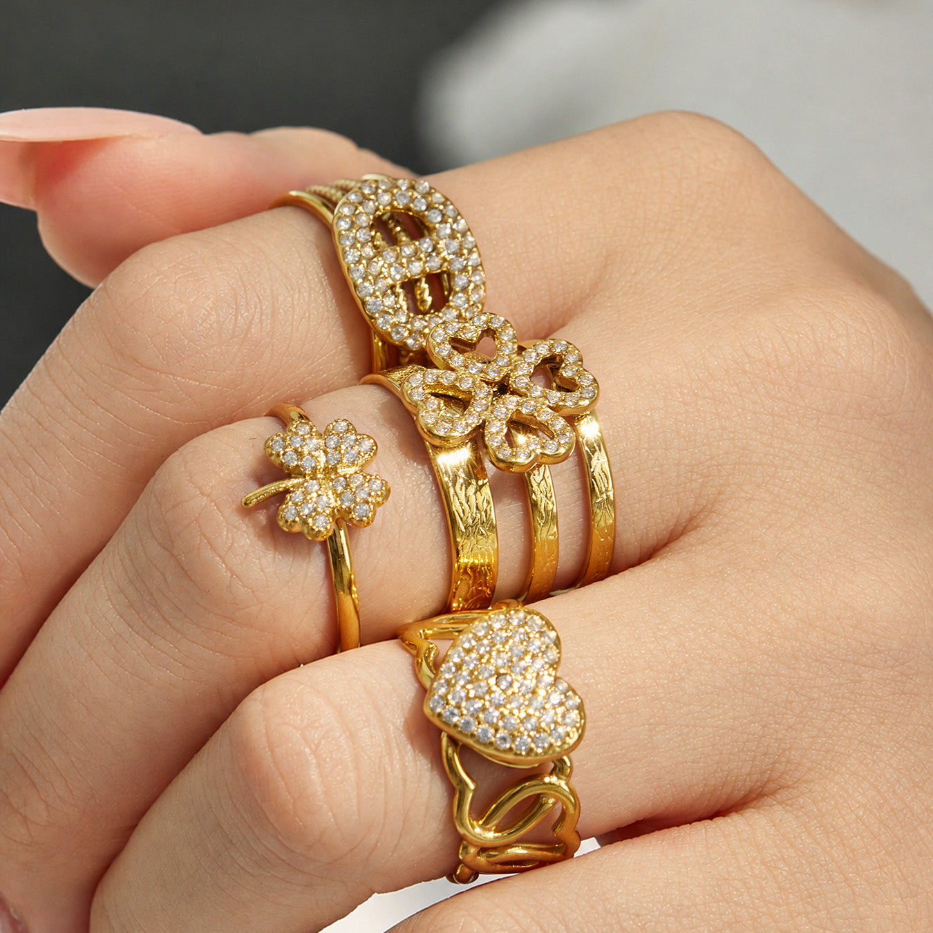 Model wearing multiple 18K PVD gold 316L stainless steel CZ open rings in mixed statement designs