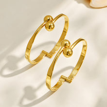 Side-angle view of a gold double ball cuff bracelet showing its open cuff structure