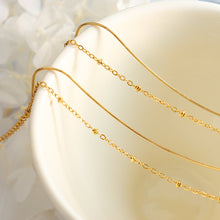 Gold double layer bracelet displayed on a soft cream jewelry stand showing layered chain details