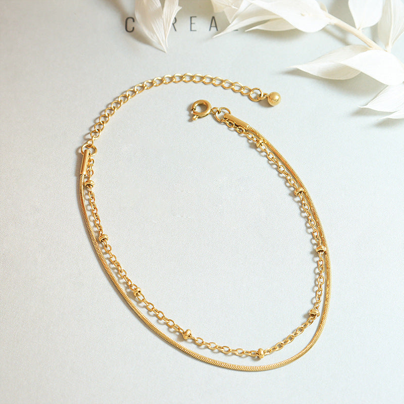Gold double layer bracelet arranged in a round shape on a light textured background