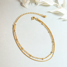 Gold double layer bracelet arranged in a round shape on a light textured background