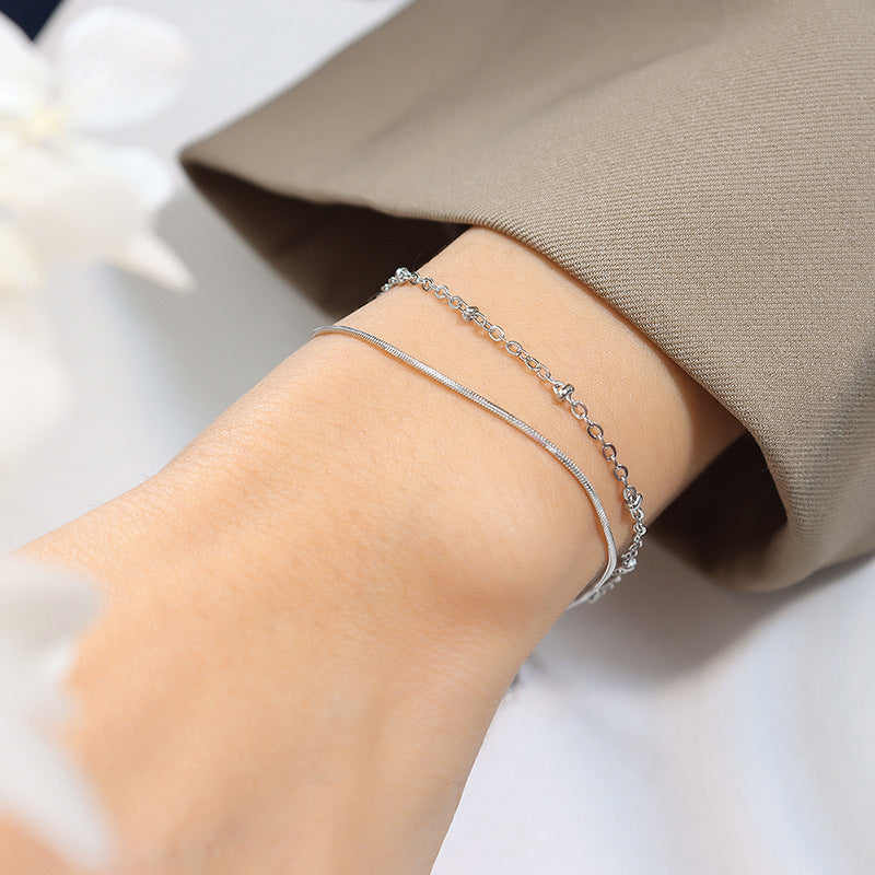 Model wearing a gold double layer bracelet with delicate snake chain styling on the wrist